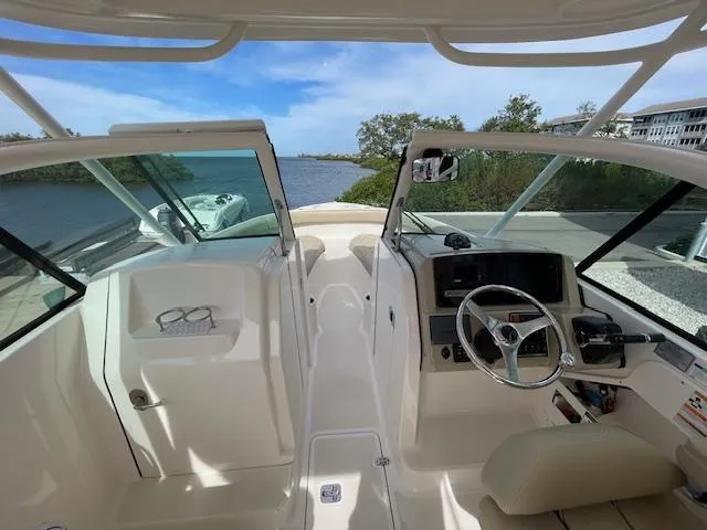 Slide: The Image of 2018 Pursuit 265 DC boat interior with steering wheel and dashboard, overlooking a scenic waterway. - 38