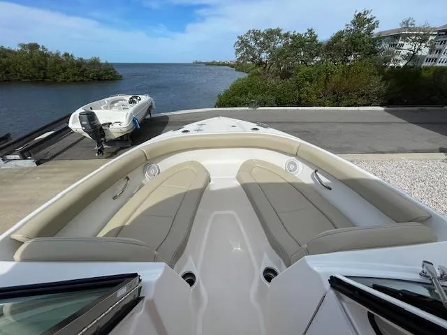 Slide: The Image of 2018 Pursuit 265 DC boat with spacious seating, docked near a scenic waterfront. - 40