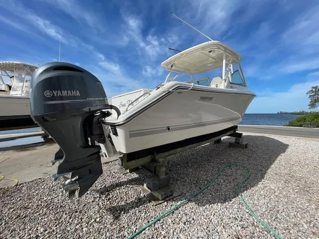 Slide: The Image of 2018 Pursuit 265 DC boat with Yamaha engine on gravel near water. - 6