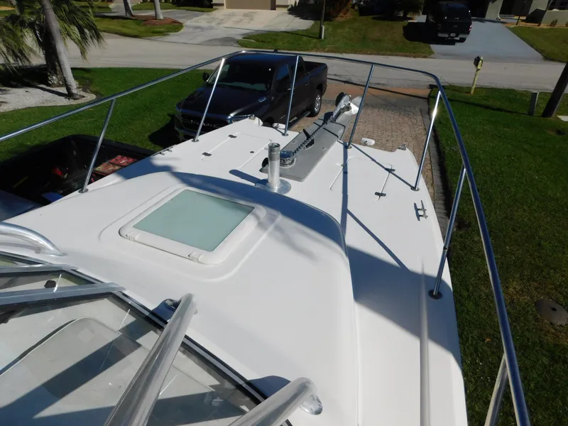 Slide: The Image of 2002 Sport-Craft 272 Sportfish boat deck with railing and hatch, parked in driveway. - 12