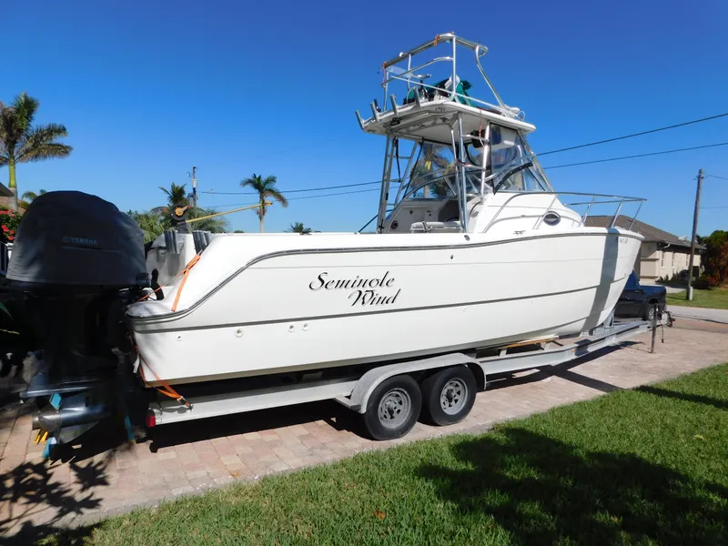 Slide: The Image of 2002 Sport-Craft 272 Sportfish boat on trailer, named "Seminole Wind," parked outdoors. - 2