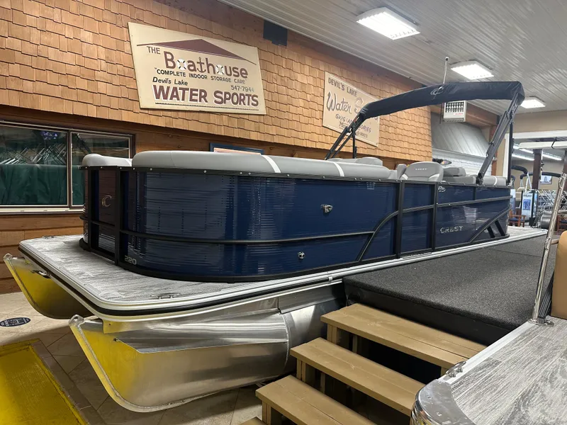 The Image of 2025 Crest Classic 220 pontoon boat displayed indoors at a water sports facility. - 1