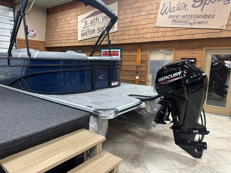 Slide: The Image of 2025 Crest Classic 220 pontoon boat with Mercury outboard motor in showroom. - 13