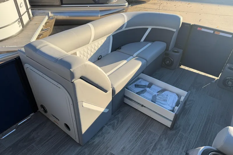 Slide: The Image of 2025 Crest Classic 220 boat interior with gray seating and storage drawer open. - 22