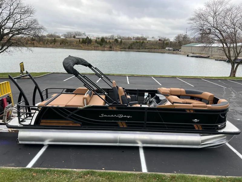 Slide: The Image of 2025 South Bay 523 ULE 3.0+ pontoon boat parked by a lake. - 3