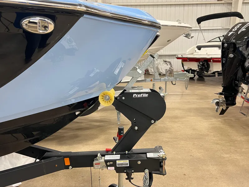 Slide: The Image of 2025 Yamaha Boats 255XD on trailer in showroom, showcasing sleek blue hull design. - 16