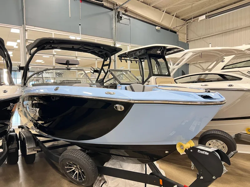 Slide: The Image of 2025 Yamaha Boats 255XD in showroom, sleek design, black and blue exterior, on trailer. - 4