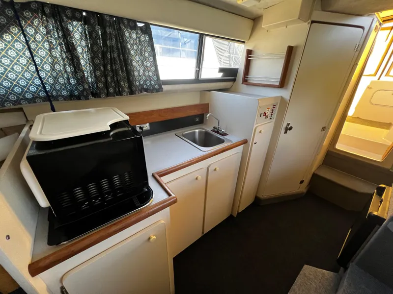 Slide: The Image of Interior of 1995 Bayliner 2859 Classic Cruiser, featuring compact kitchen with sink and appliances. - 16