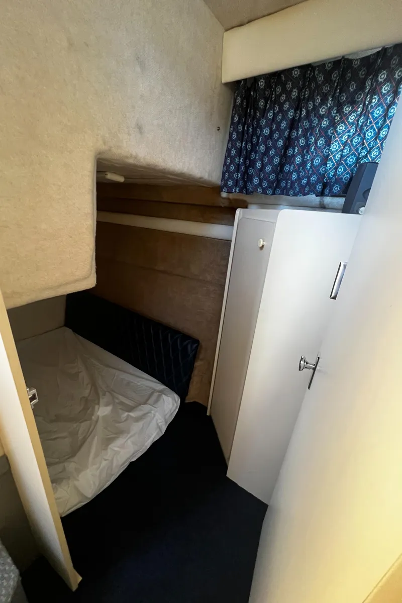 Slide: The Image of 1995 Bayliner 2859 Classic Cruiser cabin interior with bed, storage, and patterned curtains. - 18