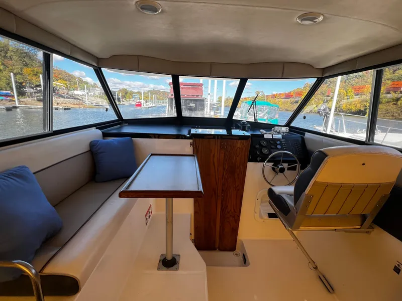 Slide: The Image of Interior of 1995 Bayliner 2859 Classic Cruiser with seating and helm, docked by scenic waterway. - 7