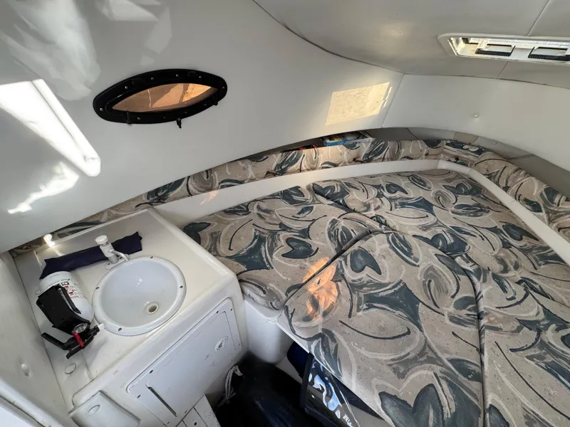 Slide: The Image of 1998 Cobia 220 Walkaround cabin interior with patterned bedding and small sink. - 12