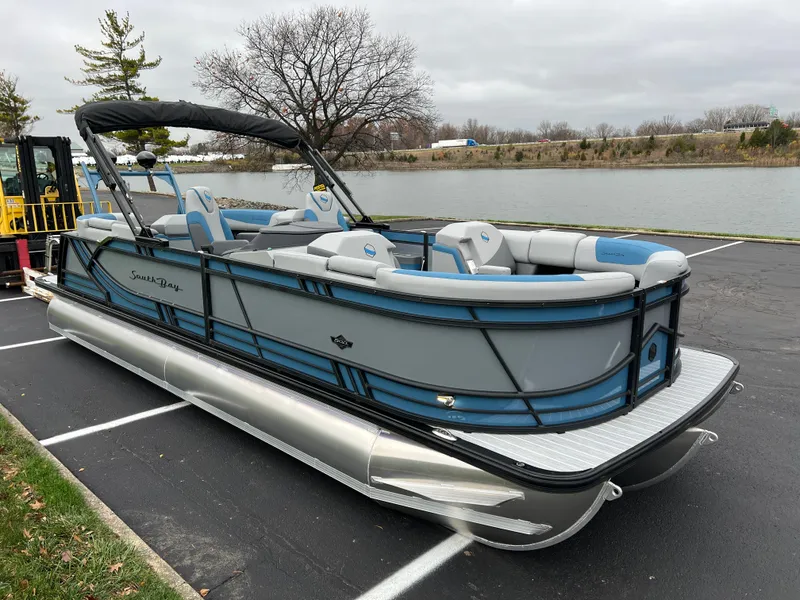 Slide: The Image of 2025 South Bay 523 RS3 3.0+ pontoon boat parked near a lake. - 2