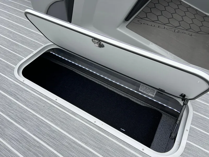 Slide: The Image of Open storage compartment on 2025 South Bay 523 RS3 3.0+ boat with striped flooring. - 29