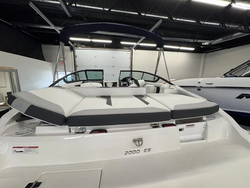 Slide: The Image of 2025 Regal 2000 ES boat with sleek white and gray seating in a showroom. - 15