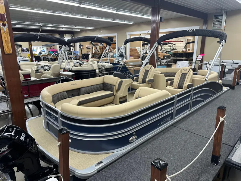 The Image of 2024 Harris Sunliner 230 pontoon boat in showroom, featuring beige seating and sleek design. - 1