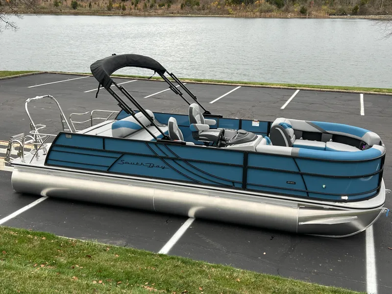 Slide: The Image of 2025 South Bay S224UL pontoon boat parked by a lake. - 1