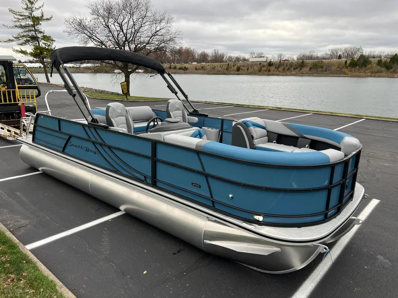 Slide: The Image of 2025 South Bay S224UL pontoon boat parked by a lakeside. - 2