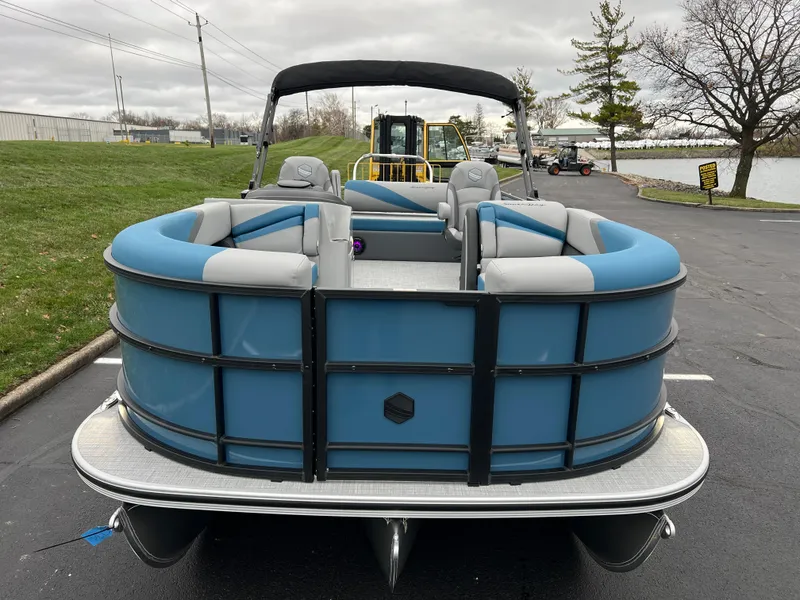 Slide: The Image of 2025 South Bay S224UL pontoon boat with blue and gray seating, parked near a lake. - 3