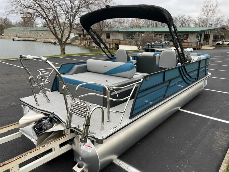 Slide: The Image of 2025 South Bay S224UL pontoon boat with canopy in parking lot near lake. - 4