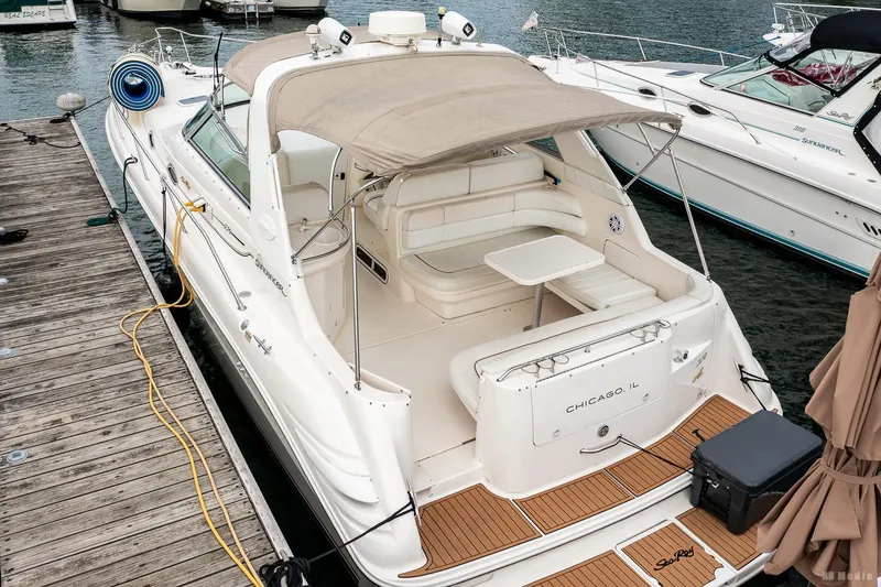 Slide: The Image of 1998 Sea Ray 330 Sundancer docked, featuring spacious seating and a canopy. - 10