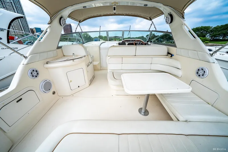 Slide: The Image of 1998 Sea Ray 330 Sundancer interior with white seating and table, docked in a marina. - 18