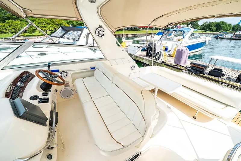 Slide: The Image of 1998 Sea Ray 330 Sundancer interior with helm, seating, and docked boats in background. - 26