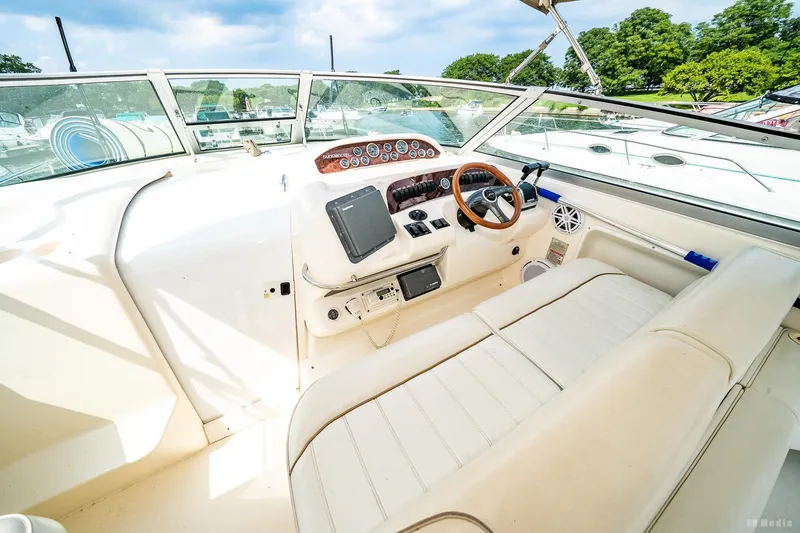 Slide: The Image of 1998 Sea Ray 330 Sundancer cockpit with steering wheel, gauges, and seating under a clear sky. - 27