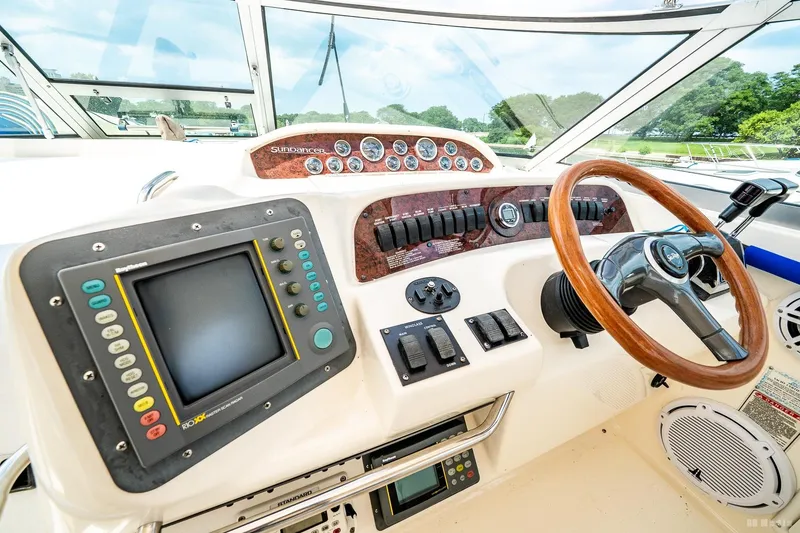 Slide: The Image of 1998 Sea Ray 330 Sundancer helm with steering wheel, control panel, and navigation display. - 28