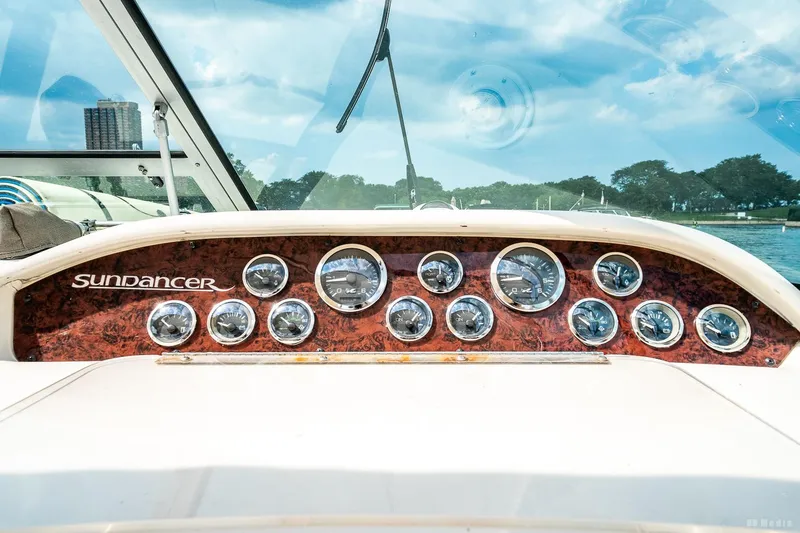 Slide: The Image of 1998 Sea Ray 330 Sundancer dashboard with gauges, wood paneling, and clear windshield view. - 31