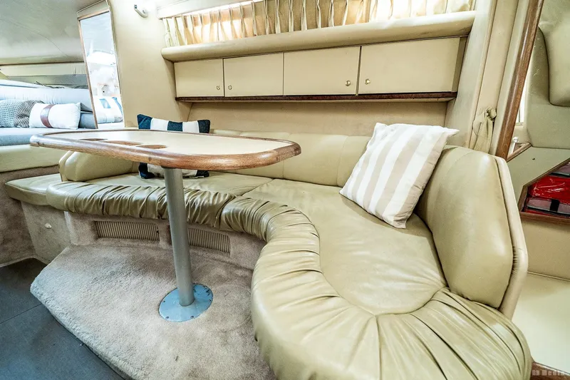 Slide: The Image of 1998 Sea Ray 330 Sundancer interior with beige leather seating and wooden table. - 35