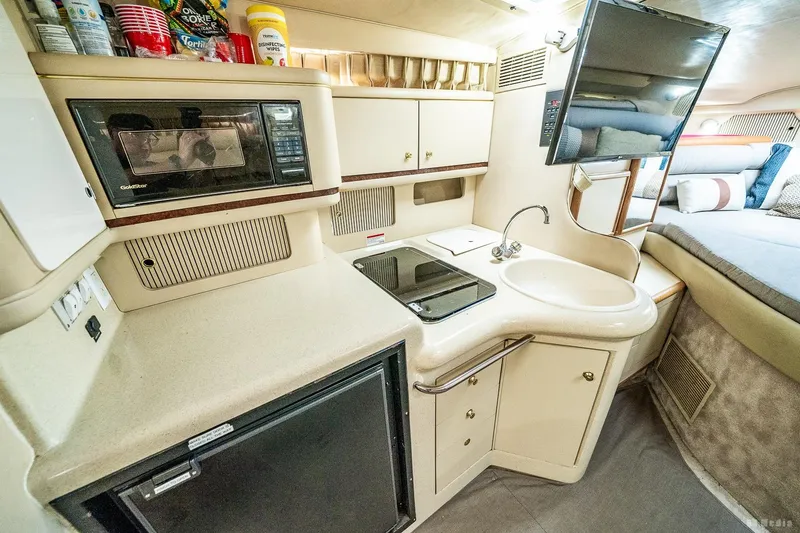 Slide: The Image of 1998 Sea Ray 330 Sundancer interior kitchen with microwave, sink, and compact design. - 39