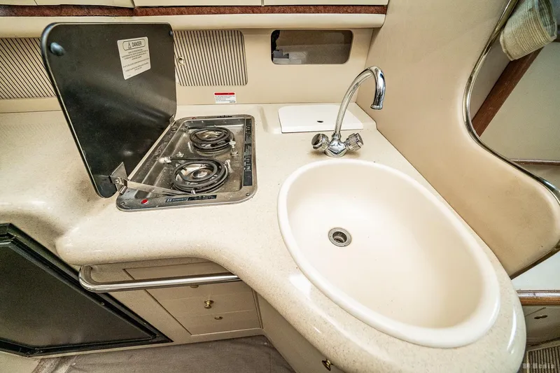 Slide: The Image of 1998 Sea Ray 330 Sundancer kitchen with stove and sink, compact and functional design. - 41