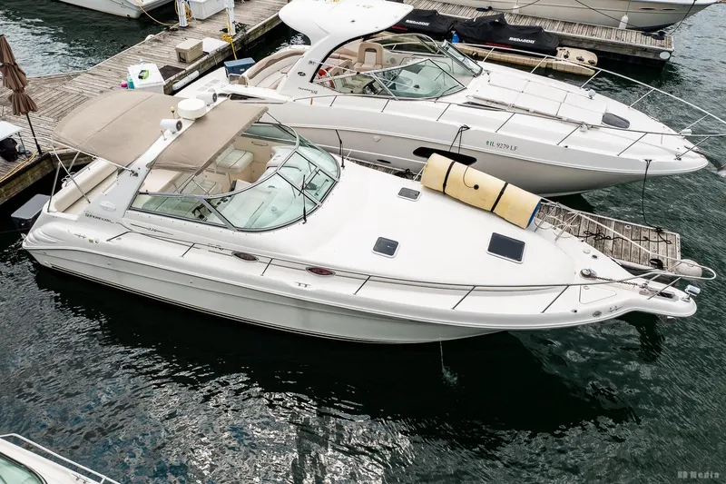 Slide: The Image of 1998 Sea Ray 330 Sundancer docked at marina, featuring sleek design and spacious deck. - 5