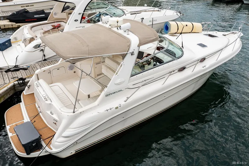 Slide: The Image of 1998 Sea Ray 330 Sundancer docked at marina, featuring spacious deck and canopy. - 8