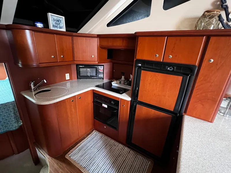 Slide: The Image of 2004 Silverton 39 Motor Yacht kitchen with wood cabinetry, sink, microwave, and refrigerator. - 16