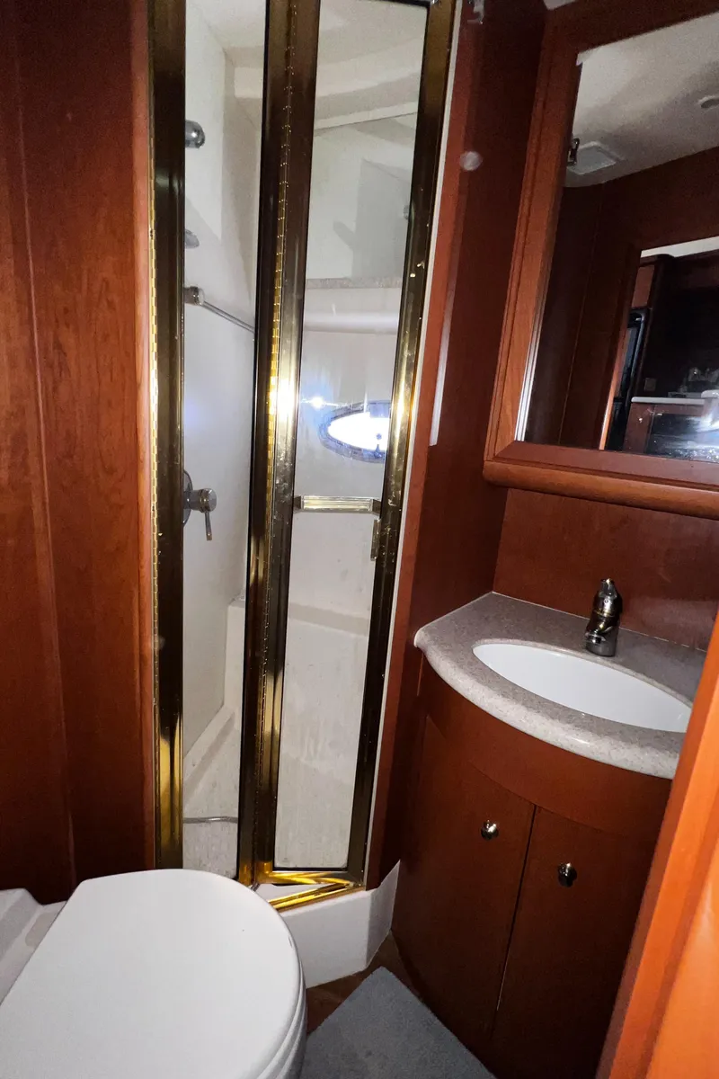 Slide: The Image of 2004 Silverton 39 Motor Yacht bathroom with shower, sink, and wooden cabinetry. - 19