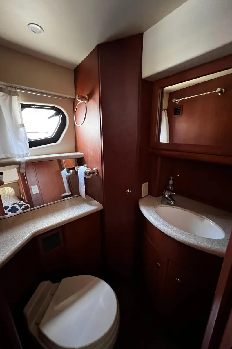 Slide: The Image of 2004 Silverton 39 Motor Yacht bathroom with sink, toilet, and porthole window. - 22