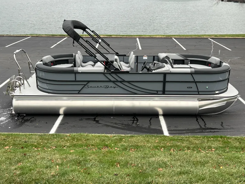 Slide: The Image of 2025 South Bay S224 Entertainer 3.0 pontoon boat parked near a lake. - 0