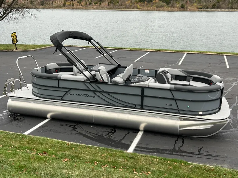Slide: The Image of 2025 South Bay S224 ENTERTAINER 3.0 pontoon boat parked near a lake. - 1