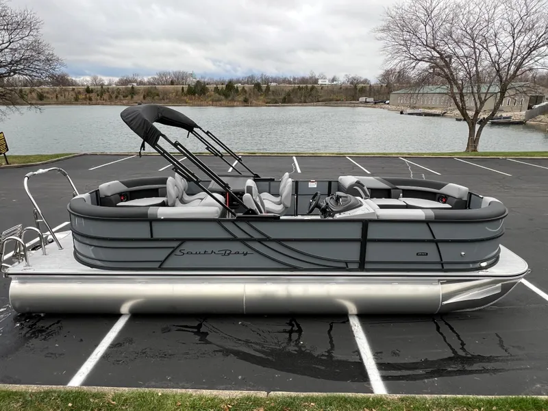 Slide: The Image of 2025 South Bay S224 Entertainer 3.0 pontoon boat parked near a lake. - 2