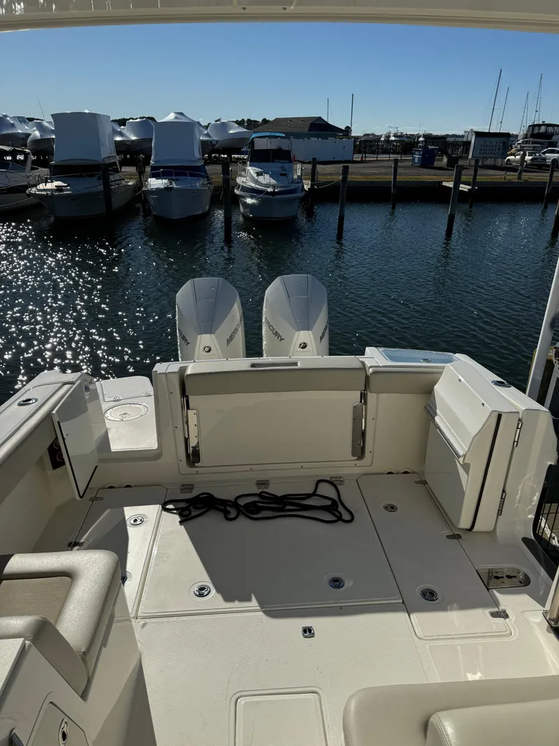 Slide: The Image of 2021 Boston Whaler 280 Vantage boat docked at marina, featuring spacious deck and twin engines. - 8