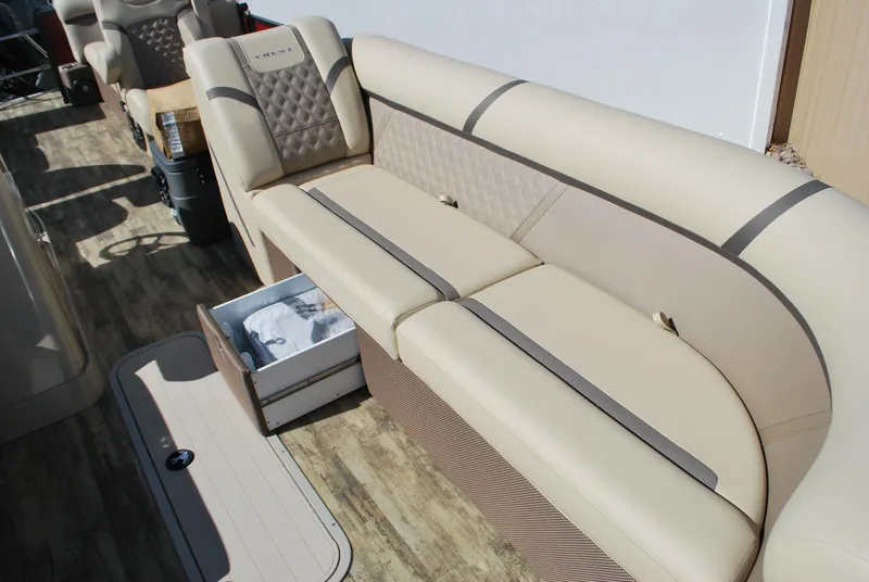 Slide: The Image of 2024 Crest Classic Platinum 240 SLC boat interior with beige seating and storage compartment. - 5