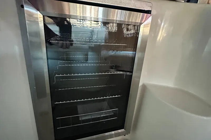 Slide: The Image of 2003 Rinker Fiesta Vee 312 boat interior fridge with wire shelves. - 15