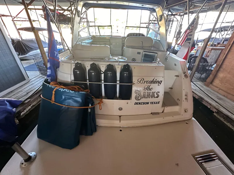 Slide: The Image of 2003 Rinker Fiesta Vee 312 boat docked, rear view with accessories and flags. - 2