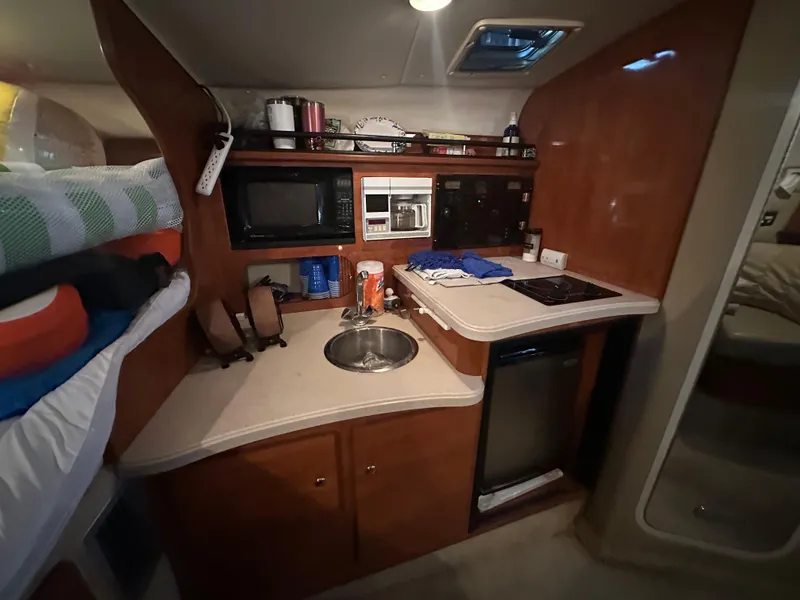 Slide: The Image of 2003 Rinker Fiesta Vee 312 boat interior kitchen with microwave, sink, and stove. - 21