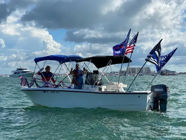 Slide: The Image of 1985 Mako 21B boat with flags on water, Yamaha motor, cloudy sky. - 0