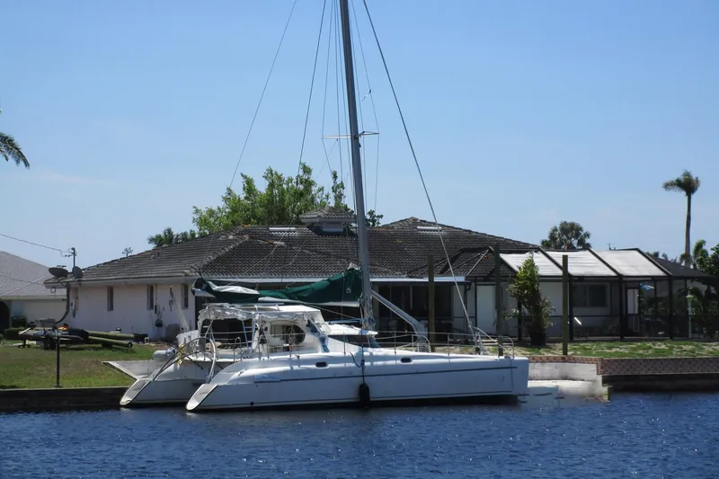 Slide: The Image of 1998 Fountaine Pajot Athena 38 catamaran docked by a waterfront house. - 0