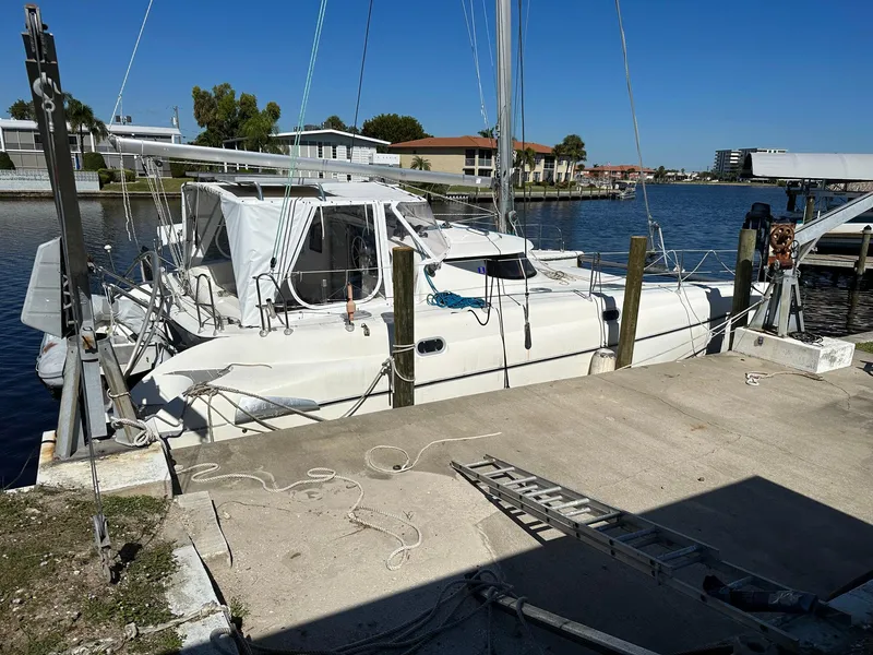 Slide: The Image of 1998 Fountaine Pajot Athena 38 catamaran docked at a marina under clear blue skies. - 38