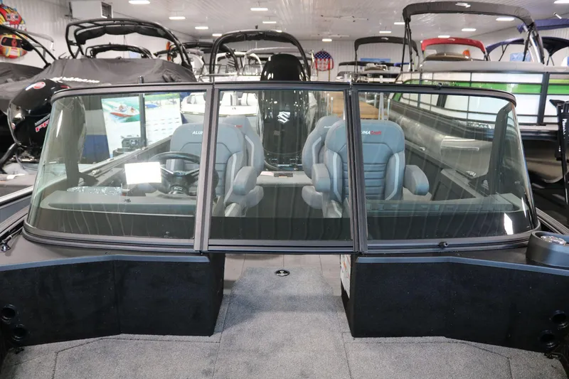 Slide: The Image of 2025 Alumacraft Competitor 175X Sport boat interior with seating and windshield in showroom. - 11