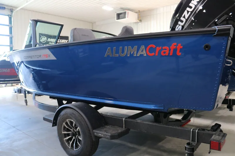 Slide: The Image of 2025 Alumacraft Competitor 175X Sport boat in showroom, blue exterior, on trailer. - 4